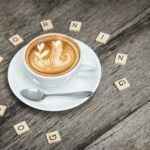 white ceramic coffee teacup beside silver teaspoon