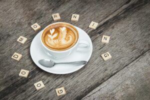 white ceramic coffee teacup beside silver teaspoon